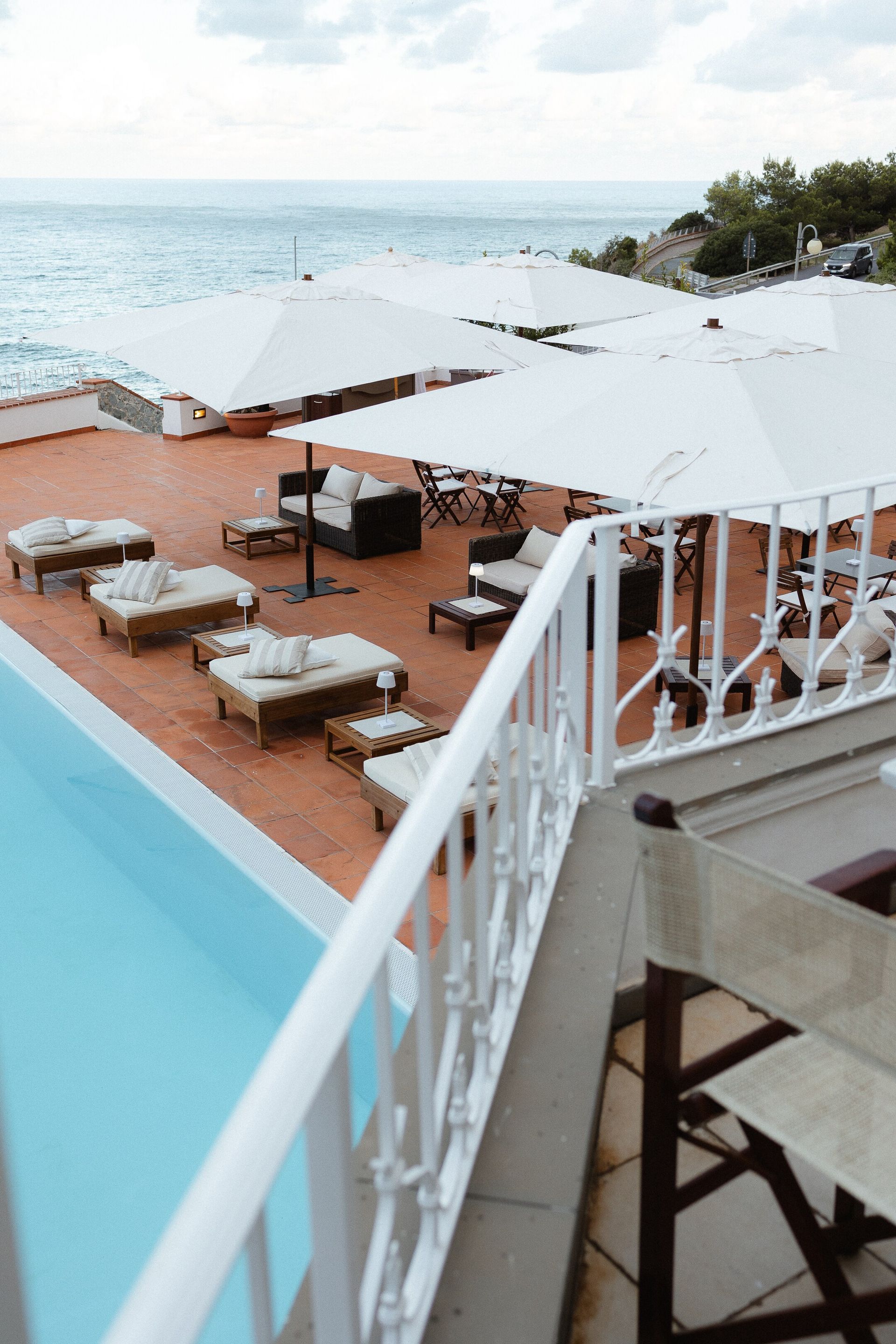 Lounge sul mare con ombrelloni bianchi e sedute imbottite